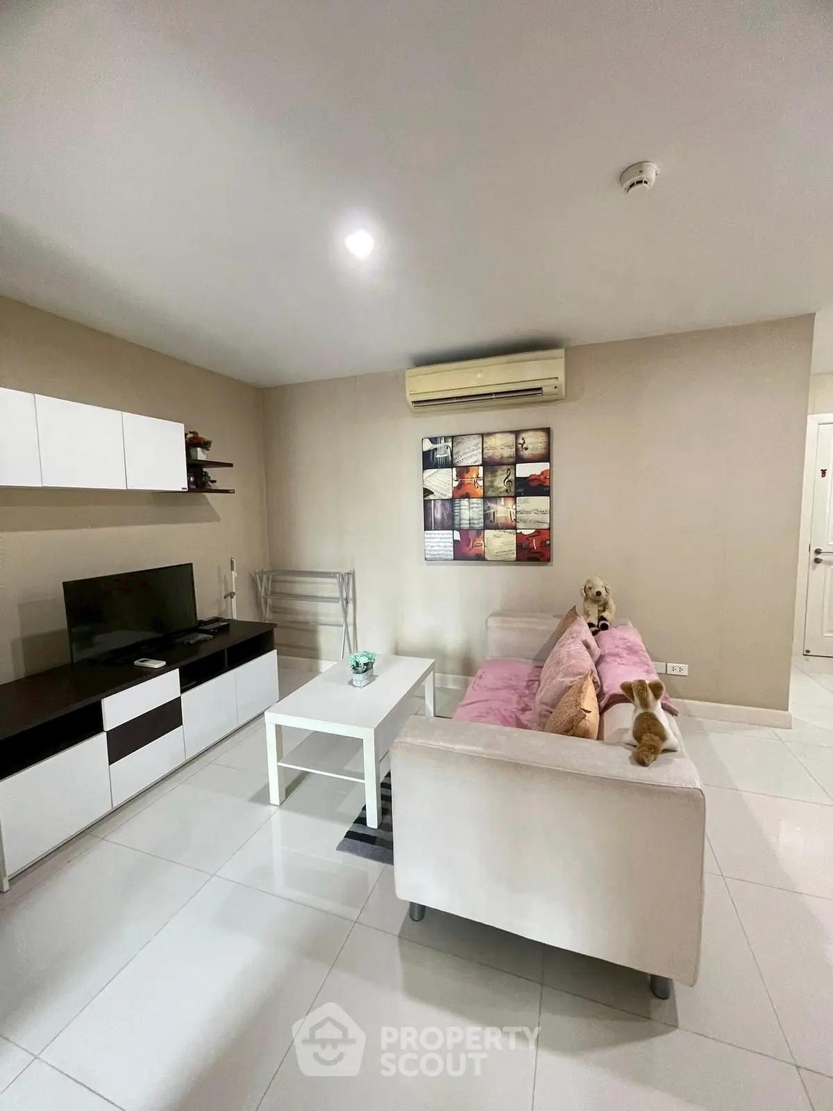 Modern living room with sleek furniture and wall-mounted TV in a cozy apartment.