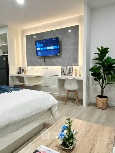 Modern bedroom with stylish decor, wall-mounted TV, and cozy workspace.