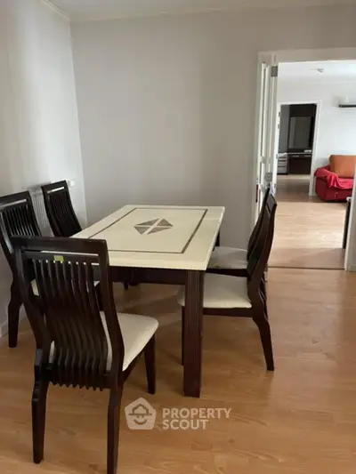 Spacious dining area with elegant wooden table set, seamlessly connected to a cozy living room with ample natural light, perfect for family gatherings.