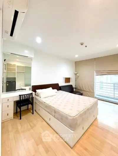 Spacious bedroom with modern furnishings and large window for natural light.