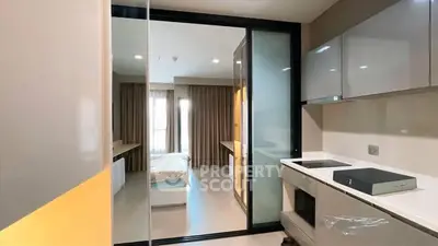 Modern studio apartment with sleek kitchen and cozy bedroom, featuring contemporary design and ample natural light.