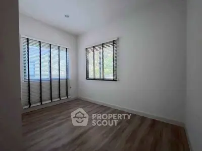 Spacious empty room with large windows and wooden flooring, perfect for customization.