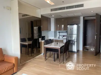 Modern apartment interior with open kitchen and dining area featuring sleek appliances and wooden flooring.