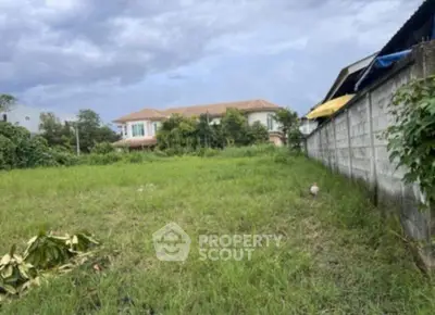 Spacious green plot of land with potential for development, surrounded by residential homes.