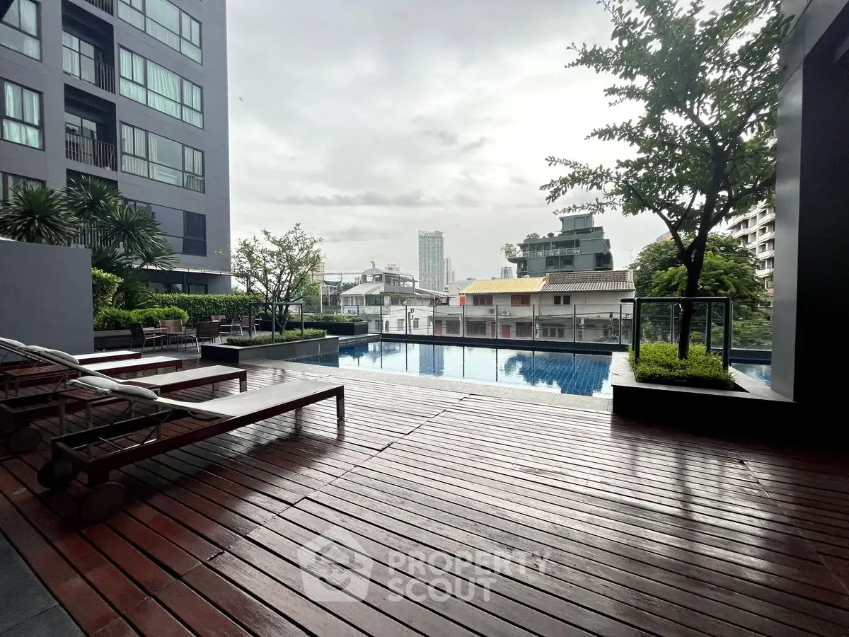 Luxurious urban poolside with wooden deck and cityscape view, perfect for relaxation and leisure.