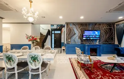 Luxurious living room with elegant decor, chandelier, and modern entertainment setup.