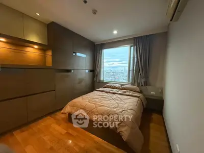 Cozy bedroom with city view, wooden flooring, and built-in storage in modern apartment.