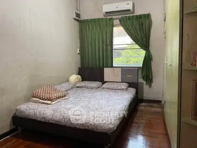Cozy bedroom with double bed, air conditioning, and green curtains.