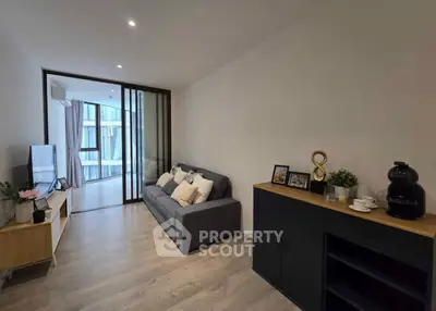 Modern living room with sleek furniture and sliding glass doors leading to a bright balcony view.