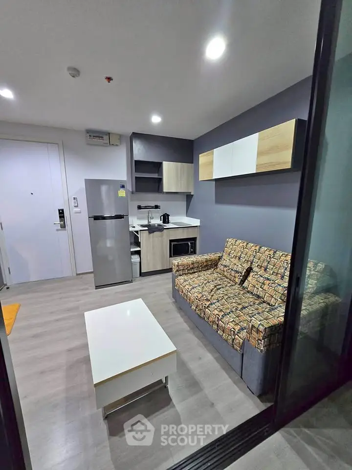 Modern living room with stylish furniture and compact kitchen in open layout apartment.
