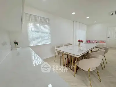 Elegant dining area with marble table and plush chairs in a modern open-plan living space.