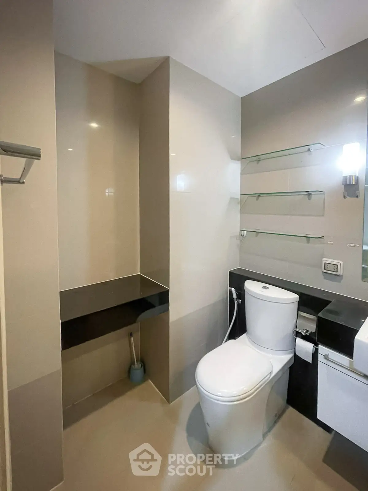 Modern bathroom with sleek fixtures and glass shelving in a contemporary apartment.