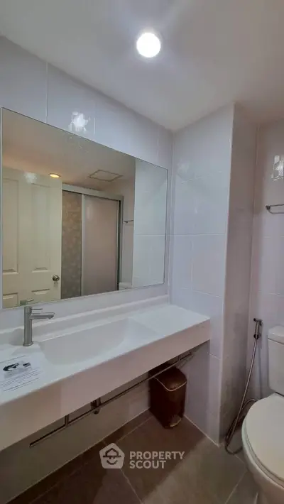 Modern bathroom with sleek fixtures and large mirror in a contemporary home.