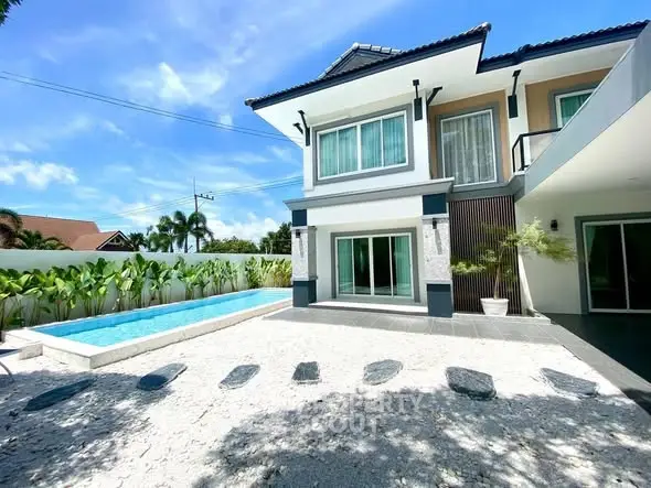 Stunning modern house with pool and spacious outdoor area under clear blue sky.
