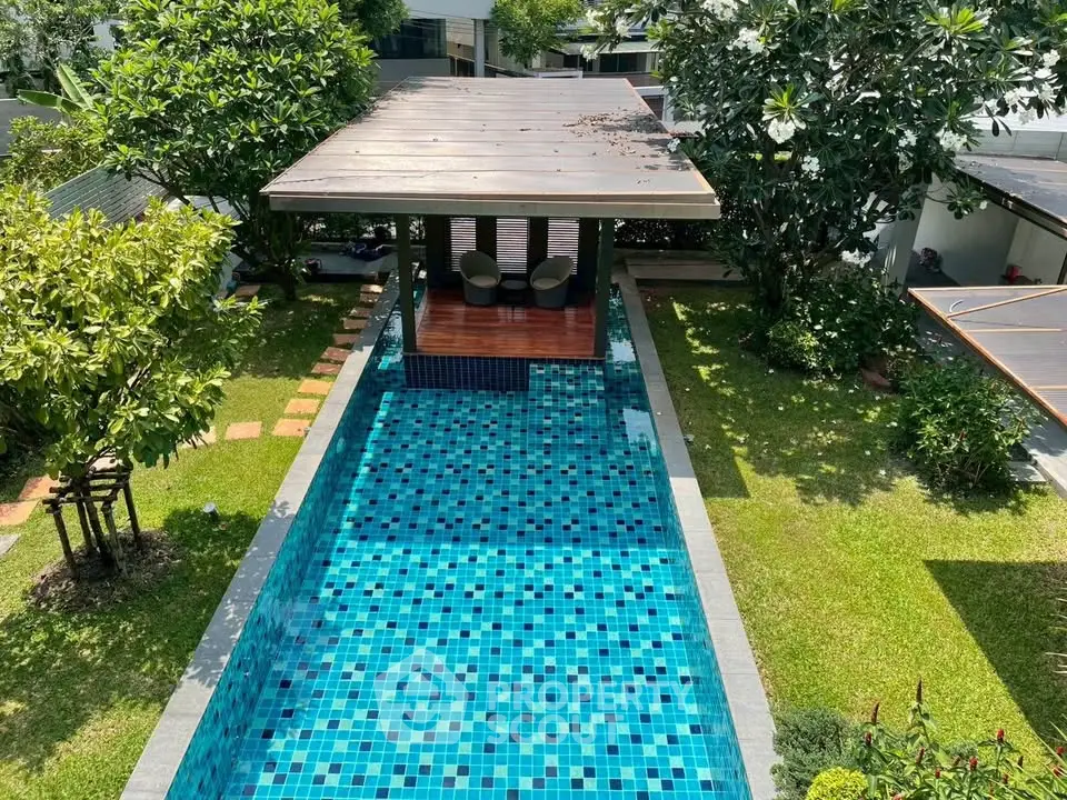 Luxurious private pool with shaded seating area in lush garden setting.