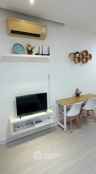 Modern living room with sleek furniture and wall-mounted TV, featuring minimalist decor and air conditioning.