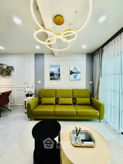 Modern living room with stylish green sofa, elegant lighting, and chic decor in a bright, airy space.