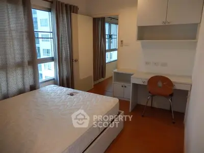 Modern bedroom with large windows and built-in desk in a high-rise apartment.