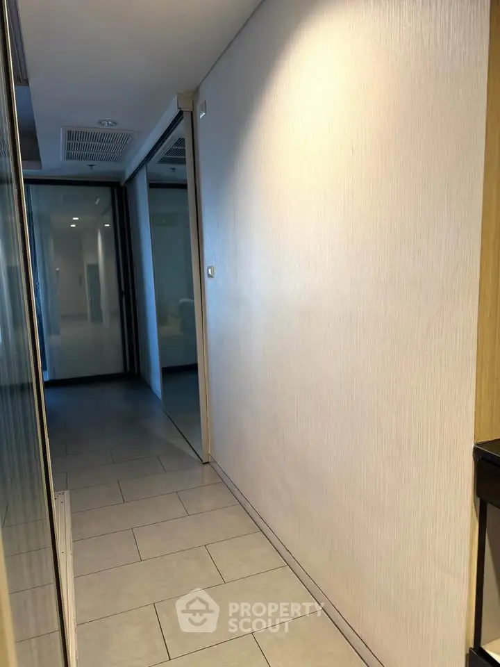 Modern hallway with sleek tile flooring and glass partition in a contemporary building.
