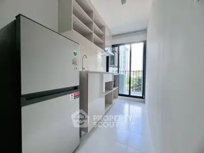 Modern kitchen with sleek appliances and open shelving, featuring a bright balcony view.