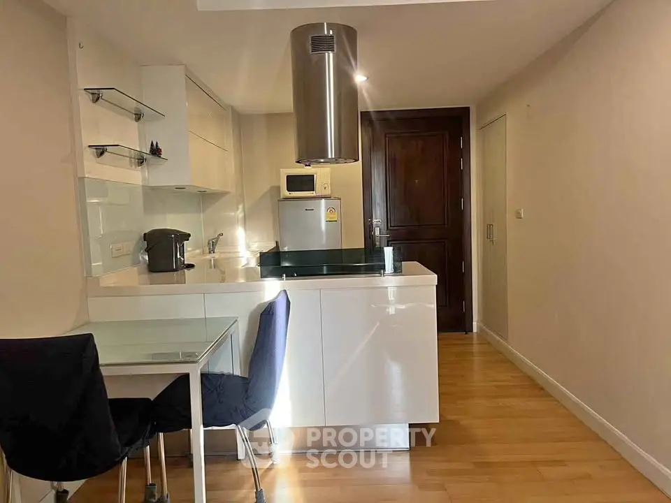 Modern kitchen with sleek design, featuring glass dining table and stainless steel appliances.