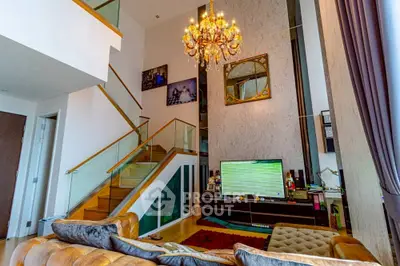 Luxurious living room with high ceiling, elegant chandelier, and modern staircase in a stylish home.
