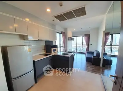 Modern open-layout kitchen with sleek cabinets and spacious living area featuring large windows and city view.