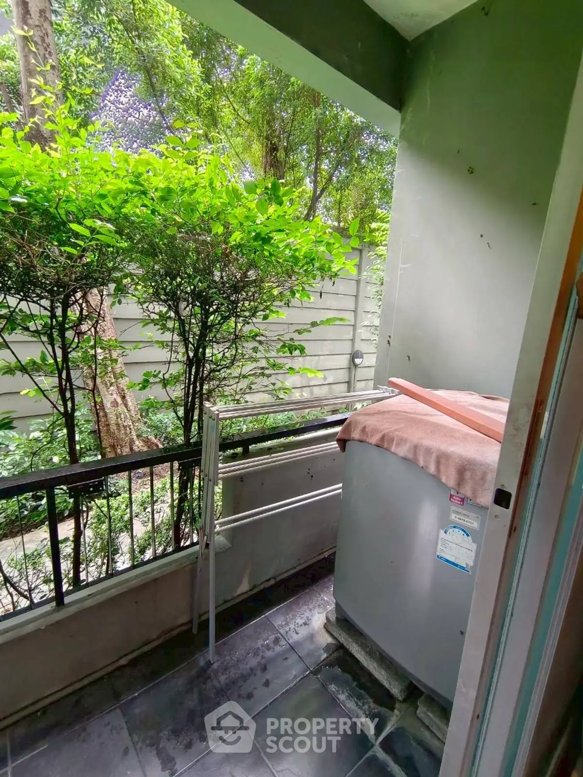 Charming small balcony with lush greenery and privacy fence, perfect for relaxation.