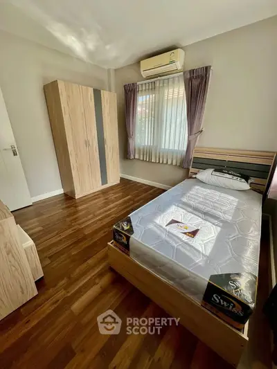 Cozy bedroom with wooden flooring and natural light, featuring a single bed and wardrobe.