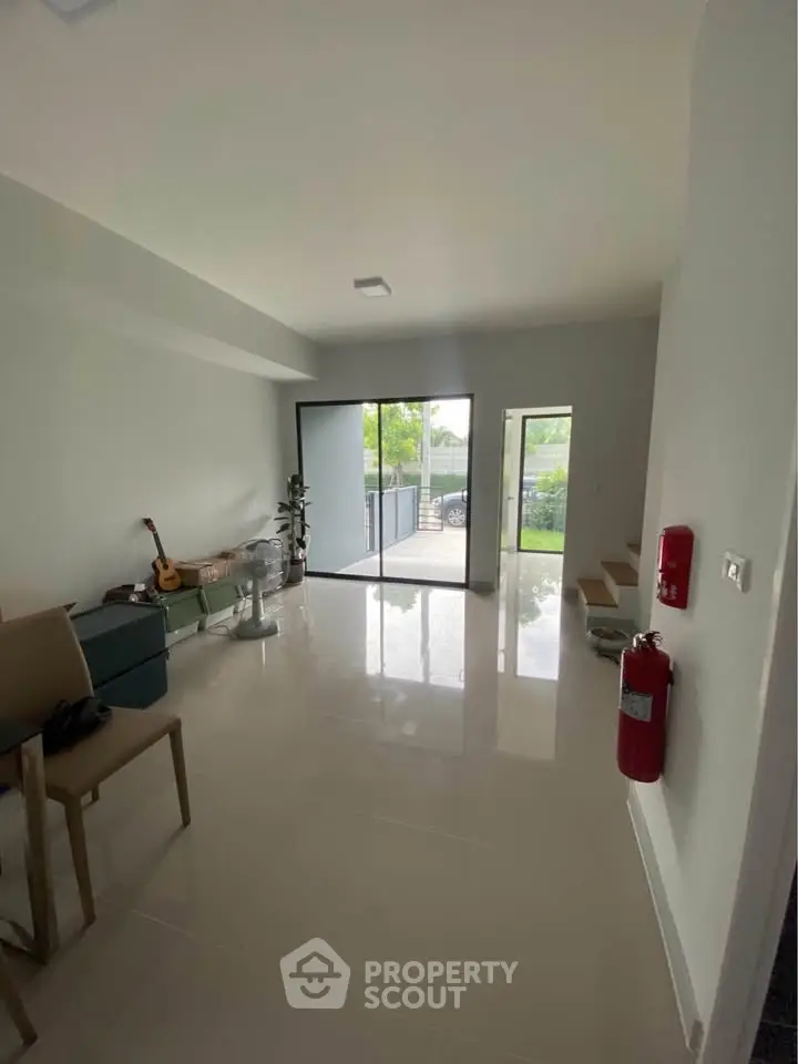 Spacious living room with glossy floors and large windows opening to a garden view.