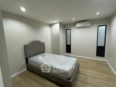 Spacious bedroom with modern design and air conditioning unit, featuring a comfortable bed and wooden flooring.
