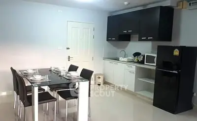 Modern kitchen with dining area, sleek black and white cabinetry, and contemporary appliances.