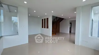 Spacious modern living room with glossy floors and staircase, perfect for family gatherings.
