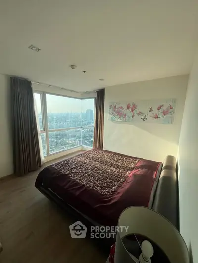 Spacious bedroom with large window offering stunning city views, elegant decor, and natural light.