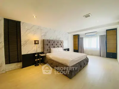 Luxurious modern bedroom with stylish decor and ample natural light.