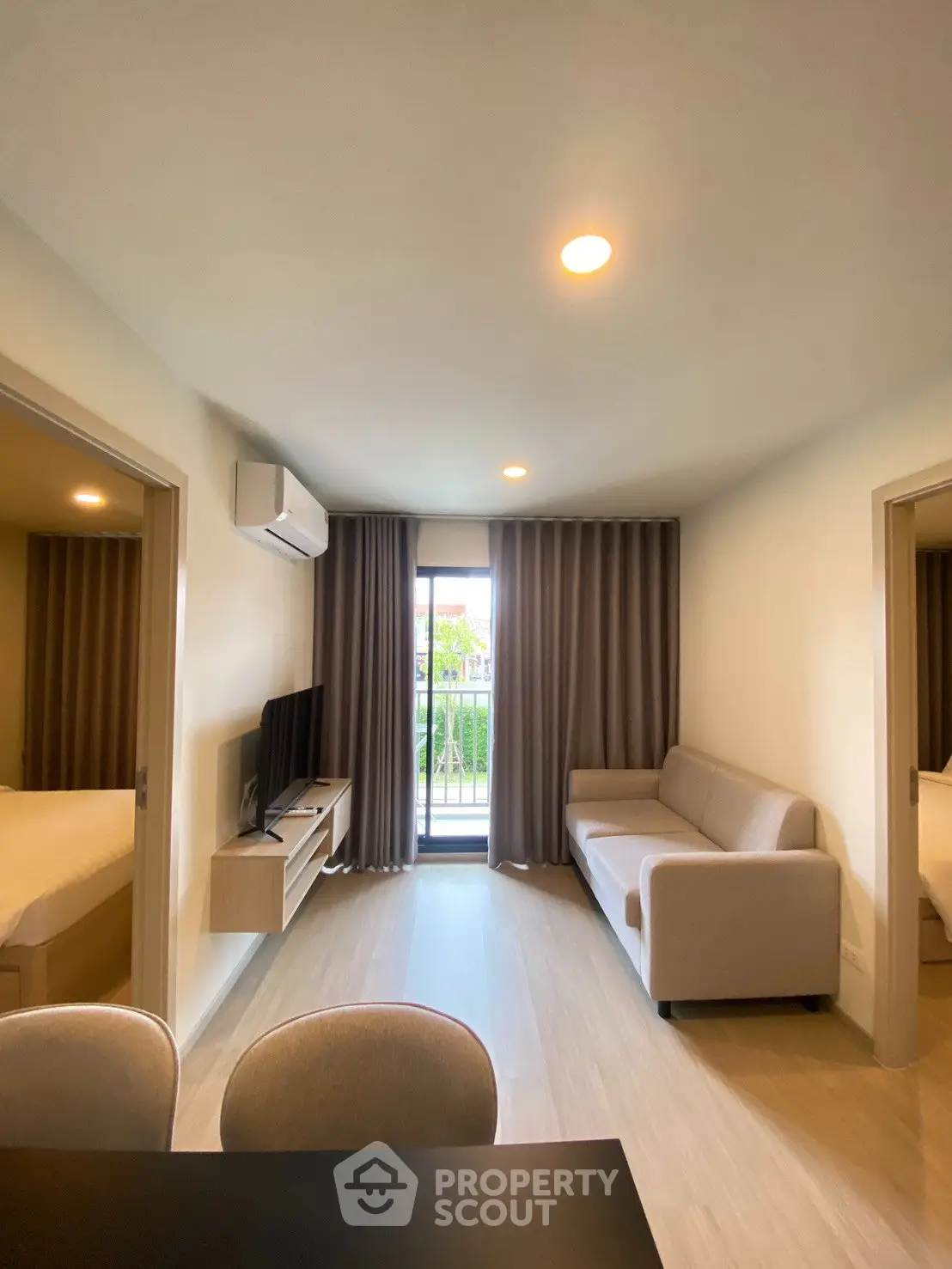 Modern living room with cozy sofa, flat-screen TV, and balcony view in a stylish apartment.