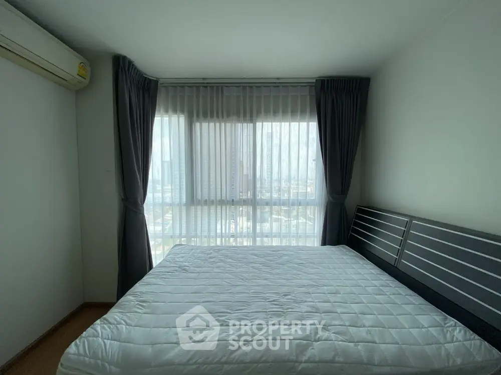 Spacious bedroom with large windows offering ample natural light and a panoramic city view, complete with air conditioning and elegant dark curtains.
