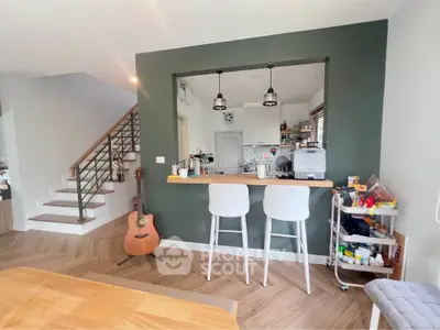 Modern open-plan kitchen with stylish bar seating and wooden flooring