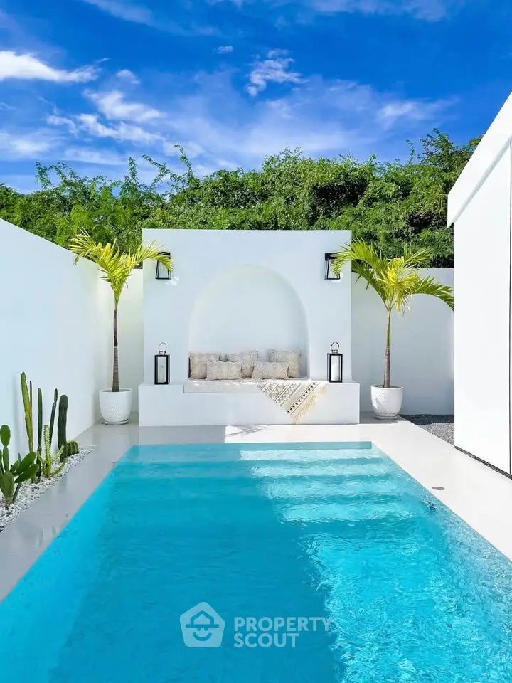 Luxurious outdoor pool area with modern seating and lush greenery, perfect for relaxation and entertainment.