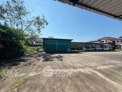 Spacious outdoor parking area with covered carports and surrounding greenery