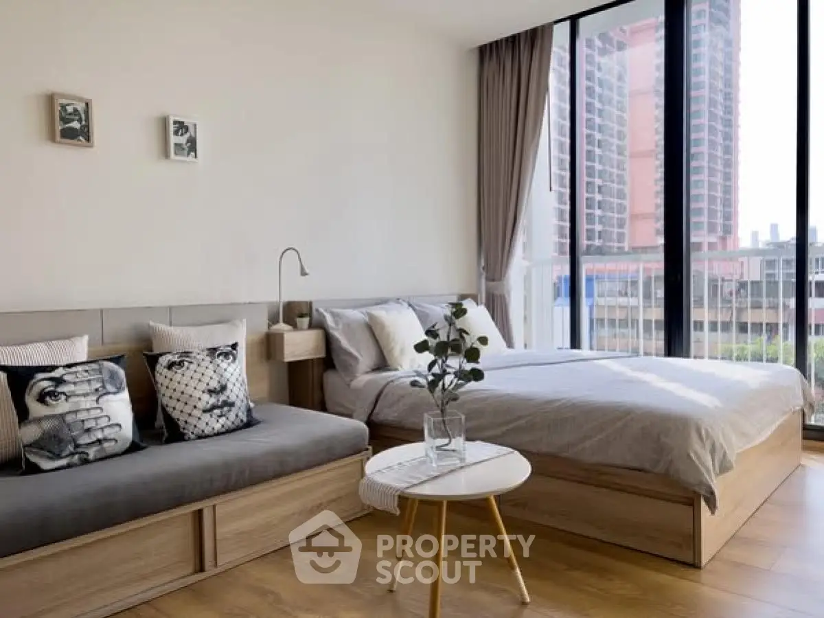 Modern bedroom with large windows and stylish decor in urban apartment.