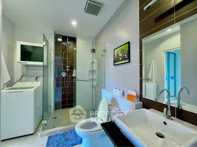 Modern bathroom with glass shower, washing machine, and stylish fixtures