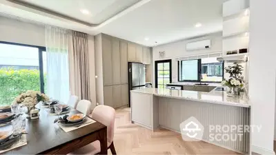 Modern open kitchen with dining area, featuring sleek cabinetry and elegant decor.