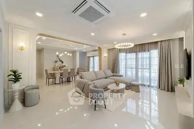 Luxurious open-plan living room with elegant decor and spacious dining area, featuring modern lighting and large windows.