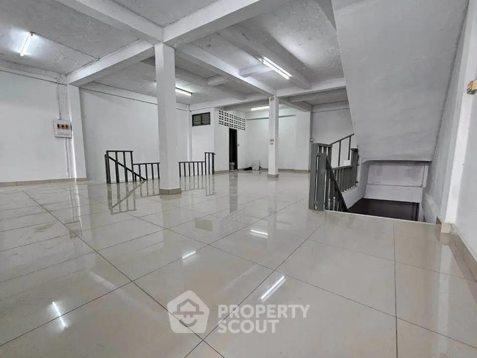 Spacious open-plan interior with tiled flooring and modern staircase, ideal for versatile use.