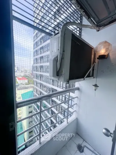 Compact balcony with city view and air conditioning unit in modern high-rise building.