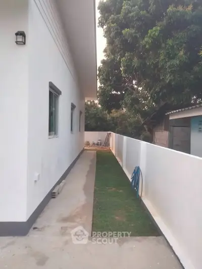 Modern exterior side view with white walls and lush greenery