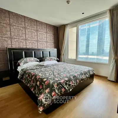 Luxurious bedroom with floral bedding and city view from large window.