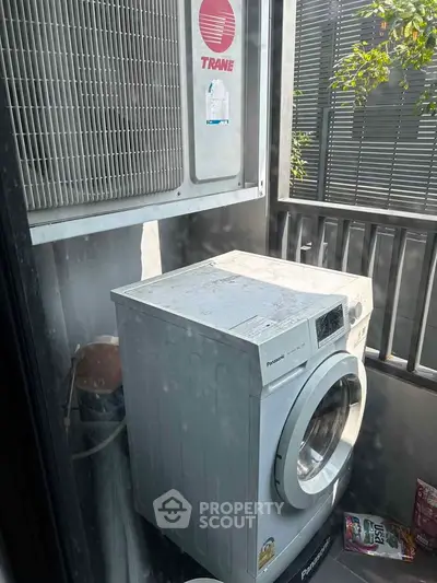 Compact balcony with washing machine and air conditioning unit, ideal for urban living.