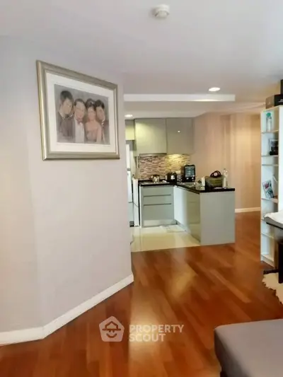 Modern open-layout kitchen with sleek cabinetry and hardwood floors in a cozy apartment.